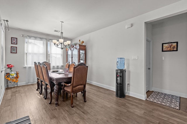 dining area featuring visible vents, baseboards, an inviting chandelier, and wood finished floors