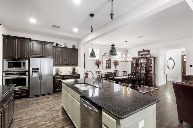 kitchen with a sink, dark wood-style floors, stainless steel appliances, arched walkways, and dark brown cabinetry