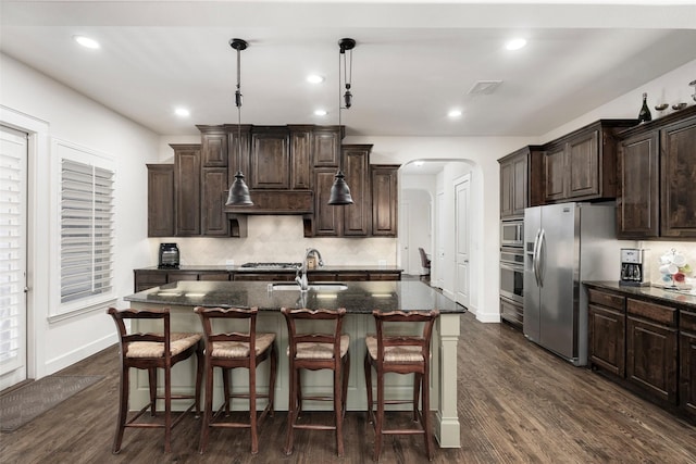 kitchen featuring visible vents, a breakfast bar, arched walkways, stainless steel appliances, and a sink