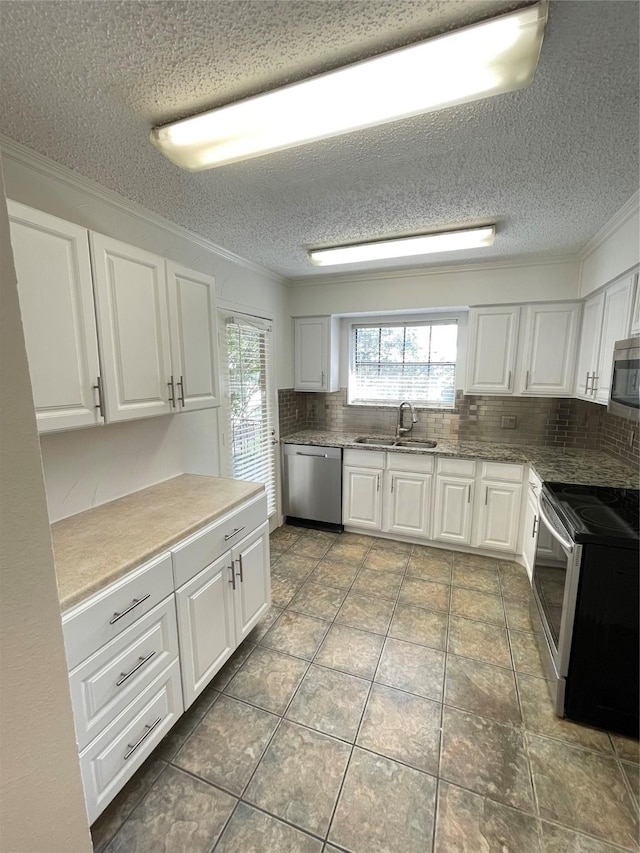 kitchen featuring a sink, backsplash, appliances with stainless steel finishes, white cabinets, and crown molding