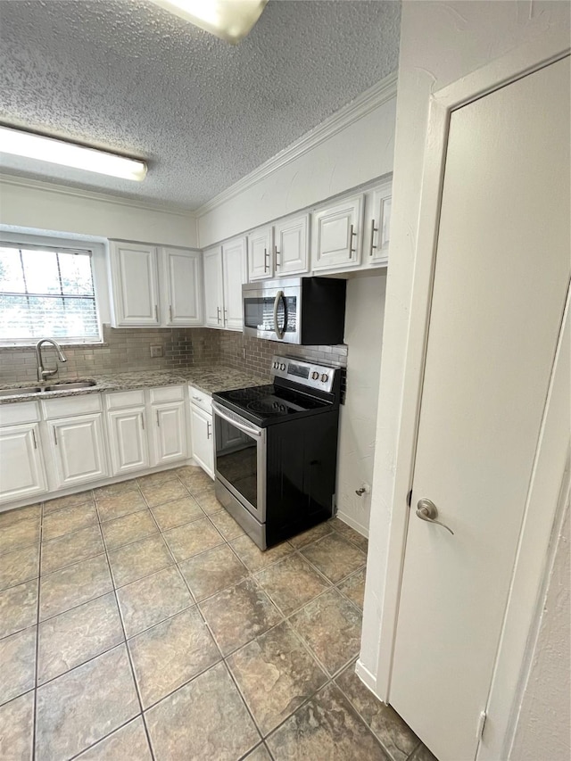 kitchen with a sink, tasteful backsplash, white cabinetry, stainless steel appliances, and crown molding