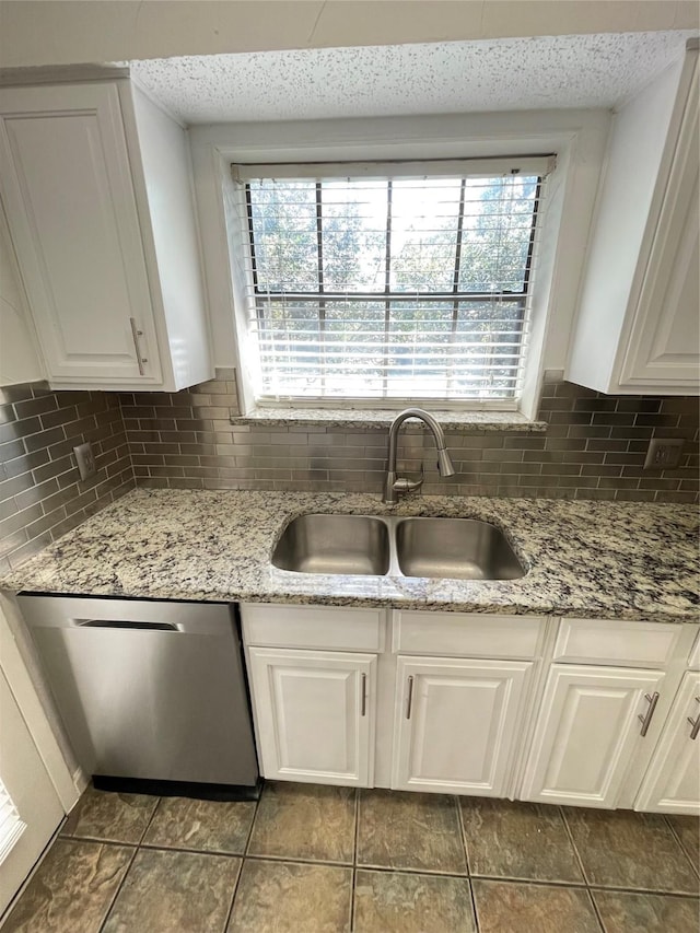 kitchen with a sink, stainless steel dishwasher, a healthy amount of sunlight, and white cabinets