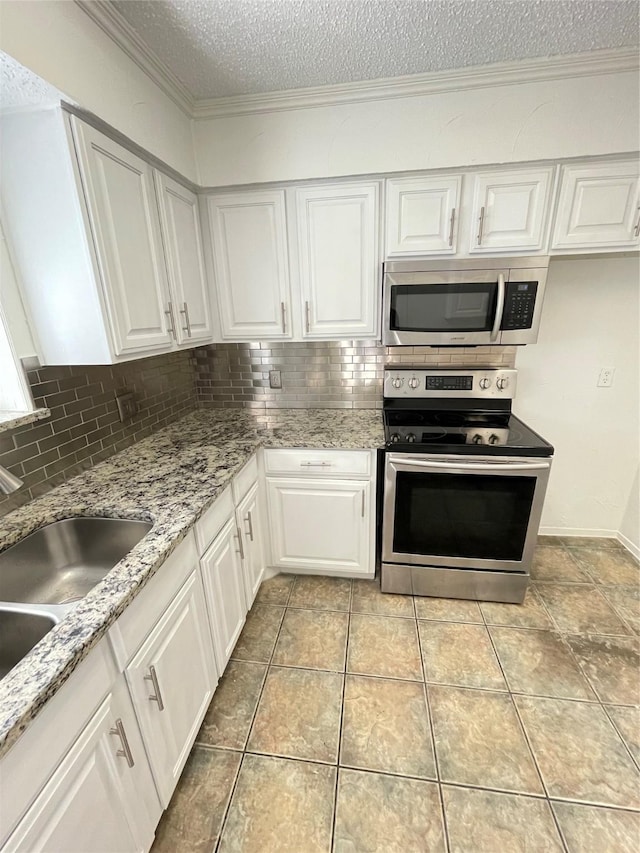 kitchen with crown molding, white cabinets, backsplash, and stainless steel appliances