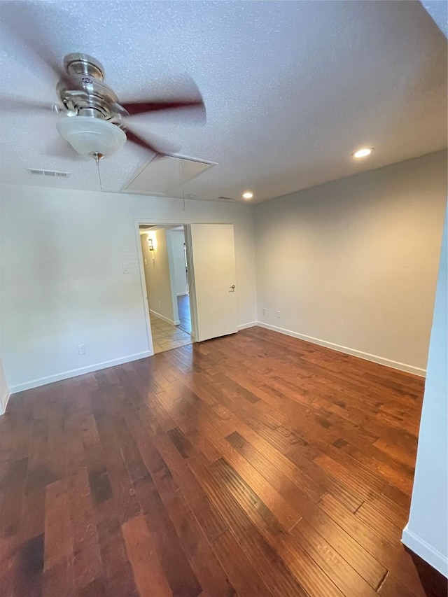 unfurnished room with baseboards, dark wood finished floors, attic access, recessed lighting, and a textured ceiling