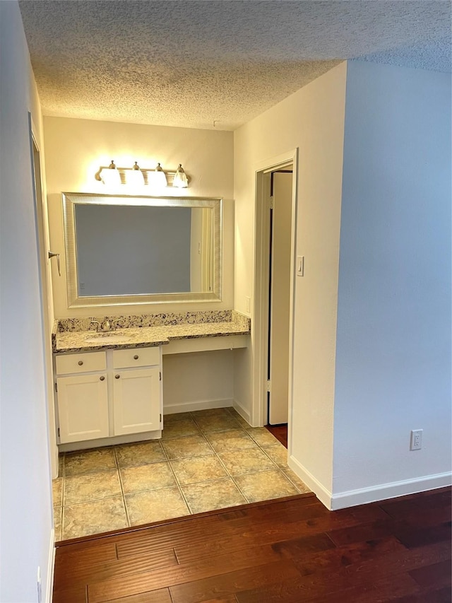 bathroom with a textured ceiling, vanity, and wood finished floors