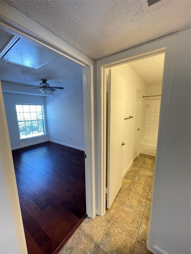 hallway featuring tile patterned flooring, baseboards, and a textured ceiling