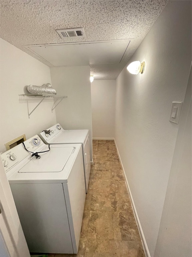 clothes washing area with visible vents, independent washer and dryer, stone finish floor, baseboards, and laundry area