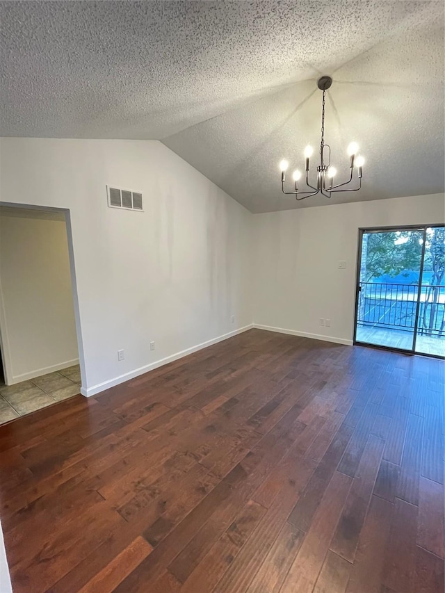 unfurnished room featuring visible vents, dark wood-type flooring, a textured ceiling, a chandelier, and vaulted ceiling