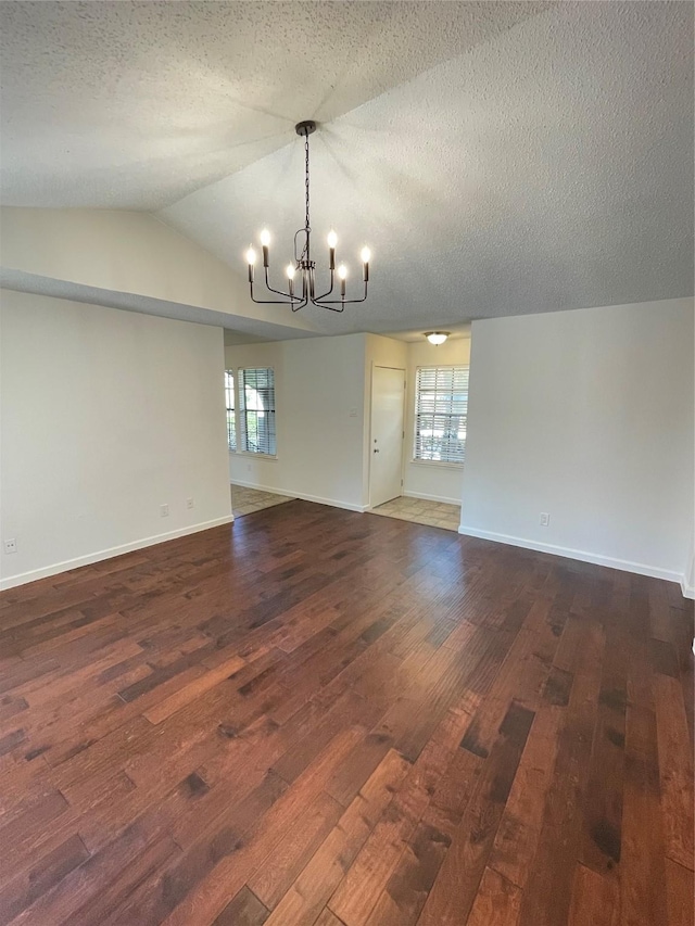 spare room featuring dark wood finished floors, an inviting chandelier, and a healthy amount of sunlight