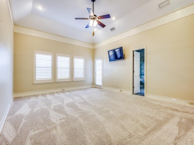 carpeted spare room featuring visible vents, a raised ceiling, baseboards, and ceiling fan