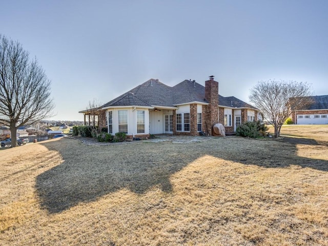 rear view of property featuring a yard, brick siding, and a chimney