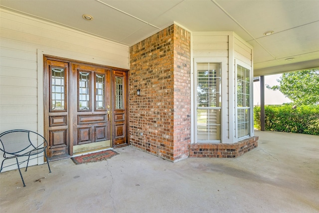 entrance to property with covered porch and brick siding