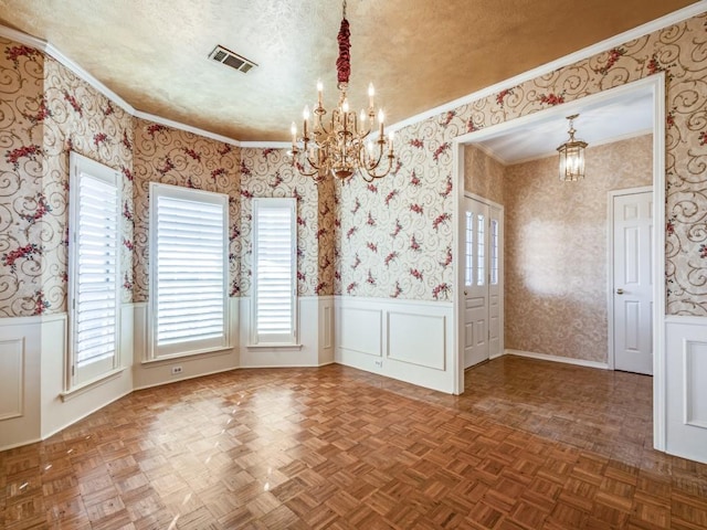 unfurnished dining area featuring a wainscoted wall, visible vents, wallpapered walls, an inviting chandelier, and a textured ceiling