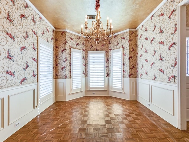 unfurnished dining area with a wainscoted wall, a textured ceiling, visible vents, and wallpapered walls