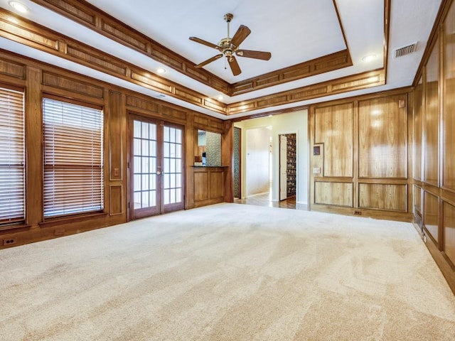 carpeted empty room with a ceiling fan, french doors, visible vents, crown molding, and a raised ceiling