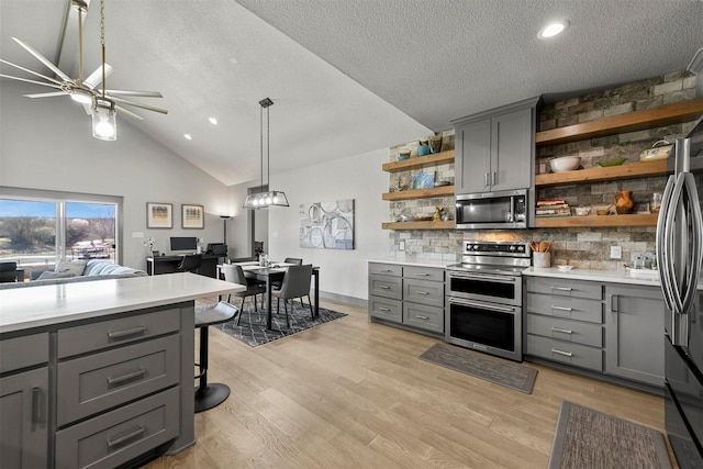 kitchen featuring open shelves, light wood-style flooring, gray cabinetry, stainless steel appliances, and light countertops