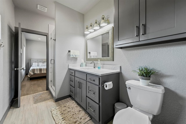 ensuite bathroom featuring visible vents, toilet, wood finished floors, ensuite bath, and a textured wall