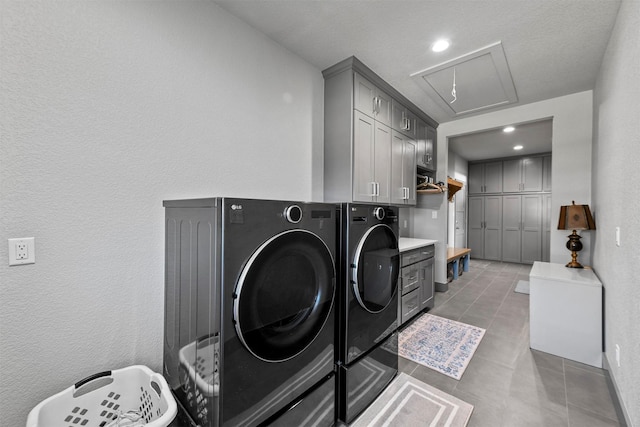 clothes washing area with washing machine and clothes dryer, tile patterned flooring, cabinet space, and attic access