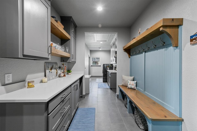 kitchen featuring tile patterned flooring, gray cabinets, light countertops, and open shelves