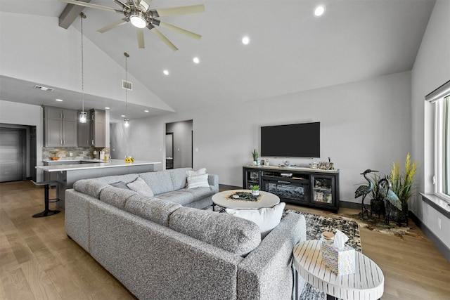 living room featuring visible vents, baseboards, high vaulted ceiling, beam ceiling, and light wood-style flooring