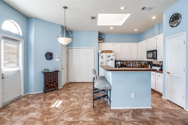 kitchen featuring visible vents, dark countertops, white refrigerator with ice dispenser, and black microwave