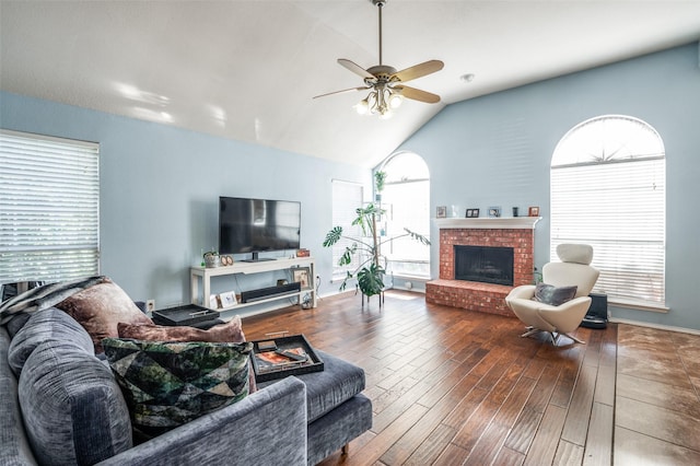 living room with a ceiling fan, wood finished floors, a fireplace, and vaulted ceiling