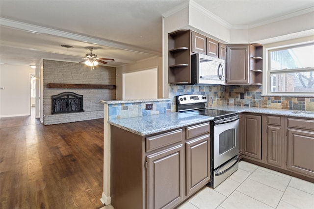 kitchen with open shelves, a brick fireplace, crown molding, and appliances with stainless steel finishes