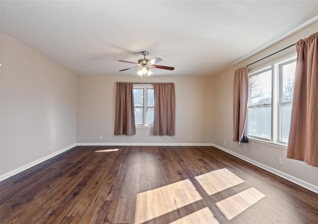 empty room with ceiling fan, dark wood-type flooring, and baseboards