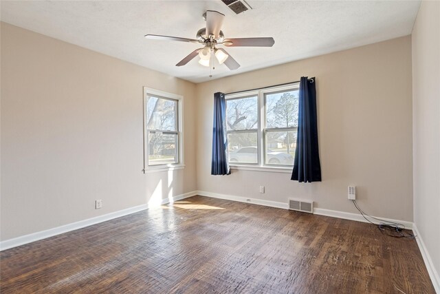 empty room featuring visible vents, baseboards, and wood finished floors