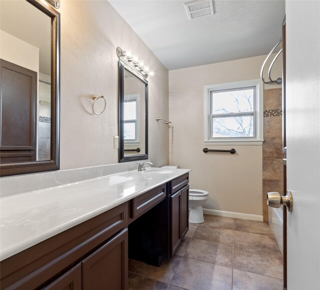 bathroom with vanity, baseboards, visible vents, tile patterned floors, and toilet