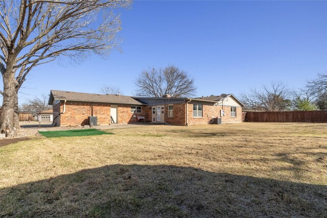 back of house featuring a lawn, fence, brick siding, and a chimney