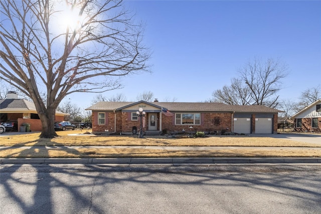 view of front of house featuring a garage, brick siding, concrete driveway, and a chimney