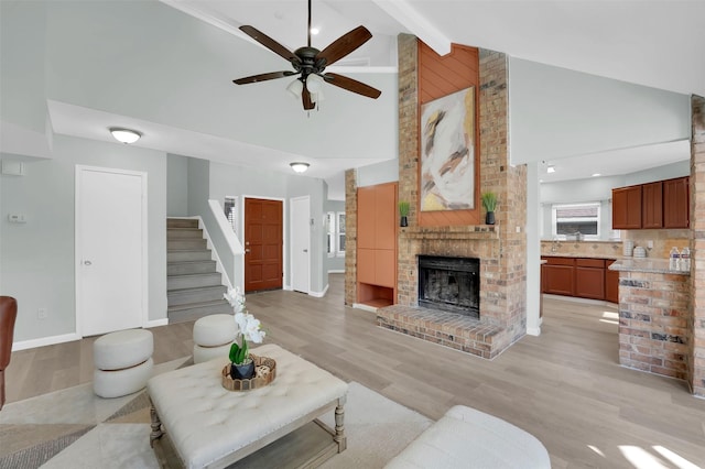 living area with a ceiling fan, a fireplace, light wood-type flooring, and high vaulted ceiling