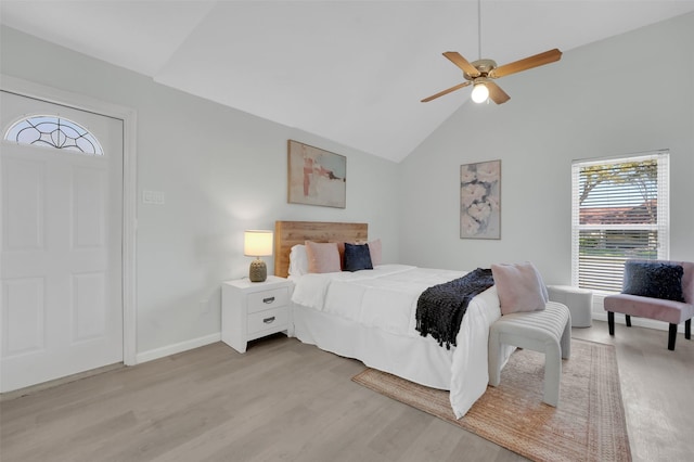 bedroom with a ceiling fan, baseboards, light wood-type flooring, and high vaulted ceiling