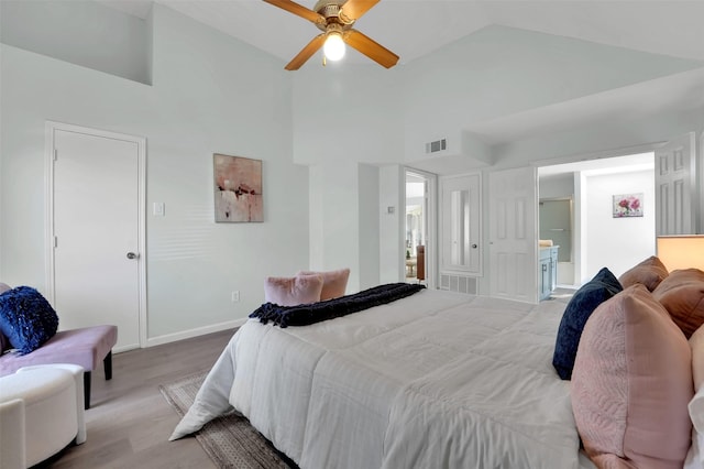 bedroom featuring wood finished floors, visible vents, ensuite bathroom, and high vaulted ceiling