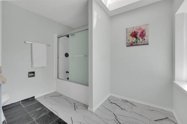 bathroom with baseboards, marble finish floor, and a skylight