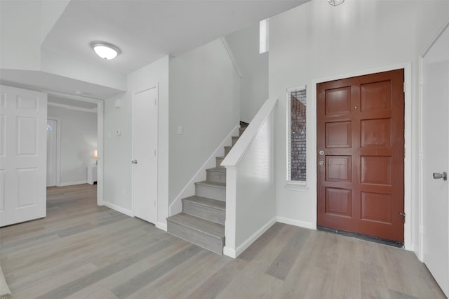 entrance foyer featuring stairway, baseboards, and wood finished floors