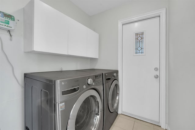 laundry room featuring washer and dryer, light tile patterned floors, and cabinet space