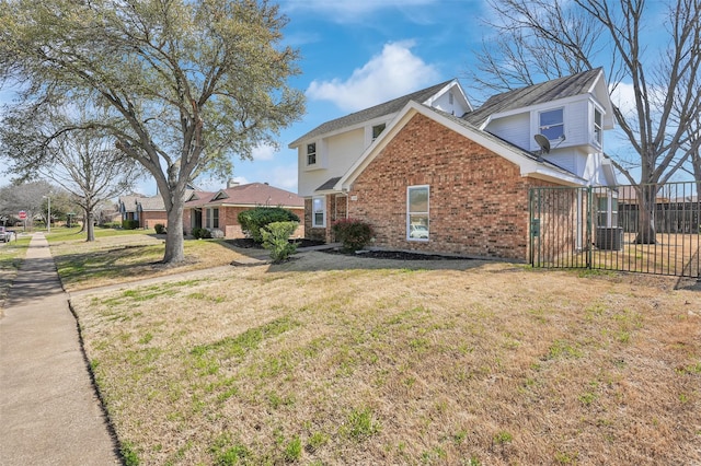 view of side of home with a yard, fence, and brick siding