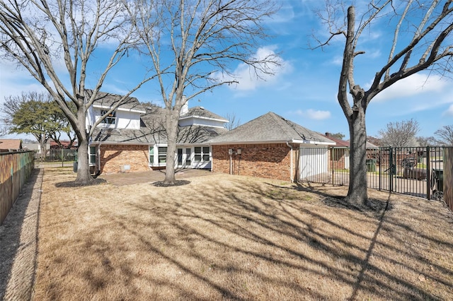 back of property with brick siding, fence private yard, and a yard