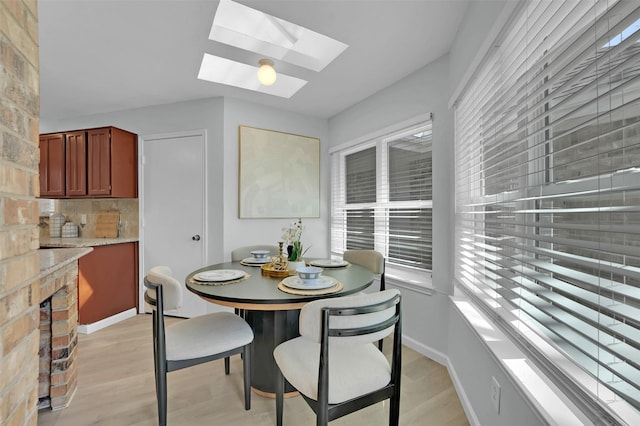 dining space featuring light wood-style flooring, baseboards, and a skylight