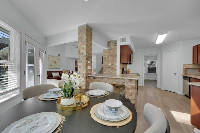 dining area with decorative columns, light wood-style floors, visible vents, and plenty of natural light