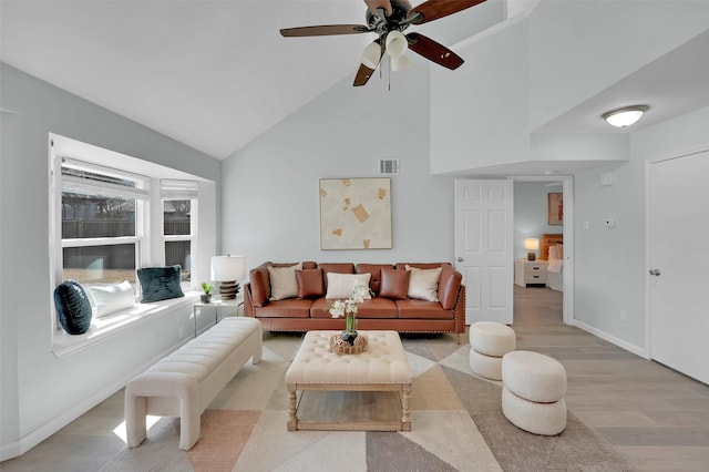 living room with visible vents, baseboards, high vaulted ceiling, ceiling fan, and light wood-style floors