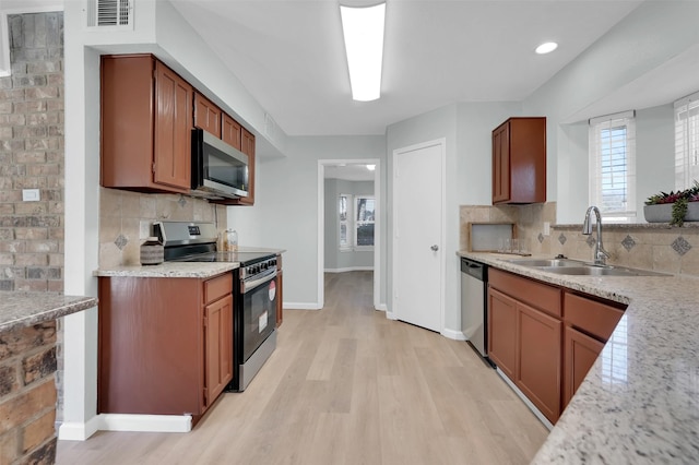 kitchen featuring a sink, decorative backsplash, light wood-style flooring, and stainless steel appliances