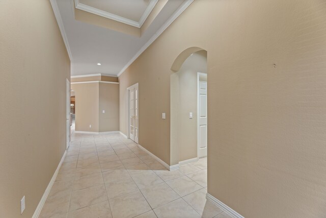 hallway with light tile patterned floors, baseboards, arched walkways, and crown molding