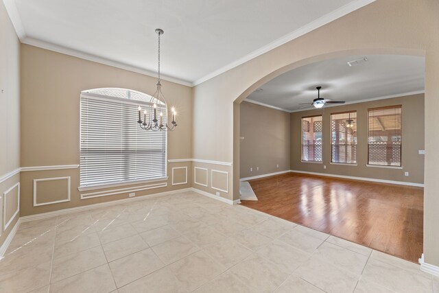 empty room featuring baseboards, arched walkways, ornamental molding, tile patterned flooring, and ceiling fan with notable chandelier