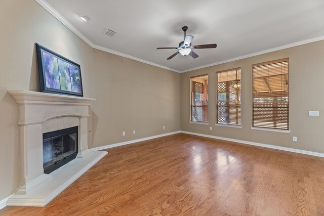 unfurnished living room with a glass covered fireplace, crown molding, visible vents, and wood finished floors