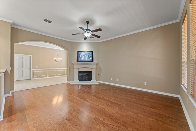 unfurnished living room featuring visible vents, ornamental molding, wood finished floors, arched walkways, and a glass covered fireplace