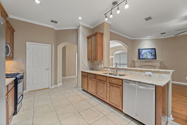 kitchen with visible vents, a sink, stainless steel dishwasher, brown cabinetry, and black range with gas cooktop