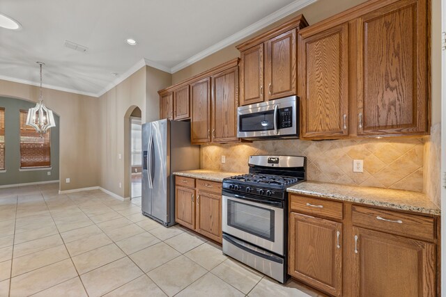 kitchen with ornamental molding, light tile patterned floors, brown cabinets, arched walkways, and stainless steel appliances